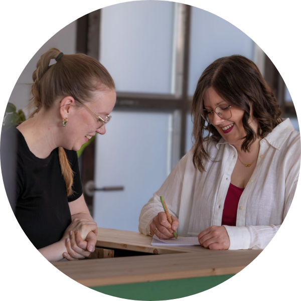 beratung Zwei Personen stehen an einer Holztheke in einer Beratungssituation