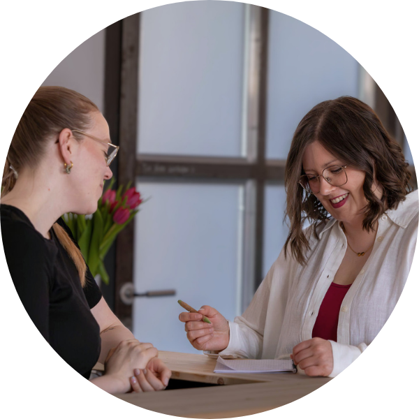 Zwei Menschen im Gespräch, mit Notizblock und einem lächeln auf dem Gesicht