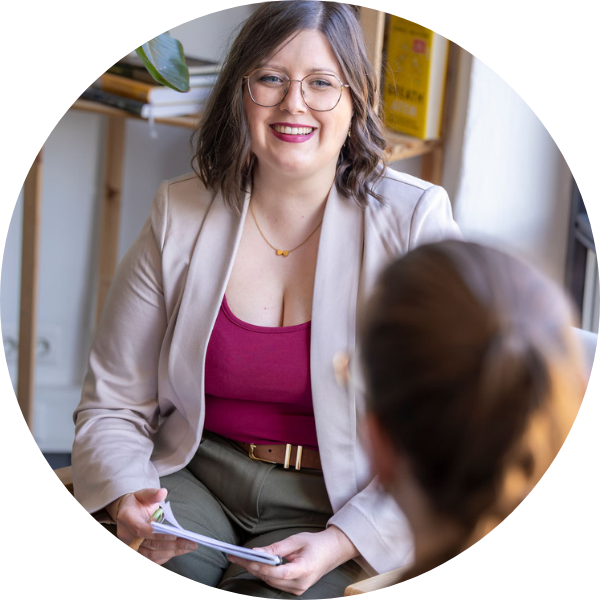 workshop-hero Jenny Schmitz lächelt ihr gegenüber an, in der Hand einen Notizblock haltend